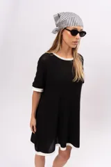 Vestido corto negro de tejido de punto calado, con cuello redondo y mangas cortas con ribete blanco.