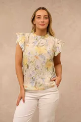 Blusa sin mangas de diseño fluido, confeccionada con estampado floral en tonos amarillos, verdes y lilas sobre base clara. Cuenta con cuello alto fruncido y mangas con volados suaves.