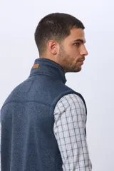 Chaleco de felpa en color azul, con cierre frontal completo, cuello alto y bolsillo vertical en el pecho.