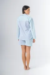 Pijama de algodón a rayas verticales celestes y blancas, compuesto por una camisa de manga larga con botones y un short con elástico en la cintura.