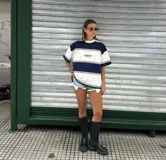 Remera de manga corta, corte oversize, con cuello redondo y diseño a rayas horizontales anchas en azul marino y blanco. Presenta un pequeño texto bordado en el pecho.