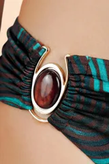Bombacha de bikini con estampado orgánico de líneas curvas en tonos marrón y turquesa. Presenta un detalle de argolla metálica dorada en el lateral izquierdo con frunces.