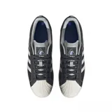Championes adidas Superstar de diseño clásico con exterior de cuero sintético en color gris oscuro, icónica puntera de goma y suela de plataforma en tono crema. Presenta las tres bandas laterales en un tono gris más claro y el nombre del modelo en letras plateadas.