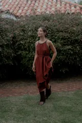 Vestido largo de crepé plissé color terracota, con escote halter adornado con perlas, falda con movimiento y lazo ajustable en la cintura.