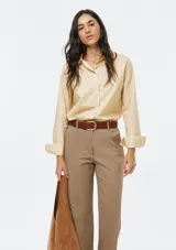 Camisa de corte clásico con cuello camisero, manga larga con puños vueltos y cierre frontal de botones. Presenta un diseño de rayas verticales finas en tono beige.