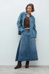 Falda midi de jean en color azul medio, con diseño de paneles verticales y corte acampanado. Presenta cierre frontal con botón y bolsillos laterales.