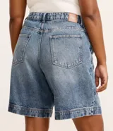 Bermuda de jean tiro alto con pinzas delanteras, bolsillos laterales tipo chino y dobladillo ancho en las perneras.