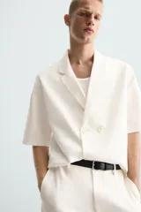 Bermuda de algodón color blanco, de corte relajado, con cintura elástica, bolsillos frontales y bolsillos traseros de plastrón. Cierre frontal con cremallera y botón.