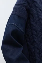 Sweater de punto trenzado en color azul marino, con cuello redondo y mangas largas. Presenta un diseño de tejido con textura en el frente y mangas lisas.