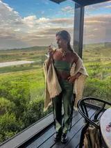 Pantalón de cuero sintético color verde safari, corte recto, con flecos largos en los laterales.