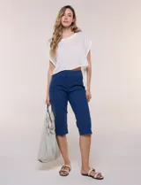 Capri de denim blanco con pretina ancha elastizada, tiro alto, bolsillos simulados al frente y bolsillos funcionales en la parte posterior, con pequeños tajos laterales en el bajo.