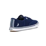 Championes de lona color azul marino, estilo casual de caña baja, con cordones azules y suela blanca con borde de goma marrón. Presentan un pequeño logo de velero blanco en el lateral exterior.
