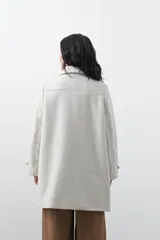 Tapado corto de paño color marrón, con diseño recto, cuello camisero y cierre frontal con broches metálicos. Cuenta con bolsillos frontales.