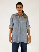 Camisa de lino color celeste con bolsillos frontales, cierre de botones y mangas largas con presilla para arremangar.
