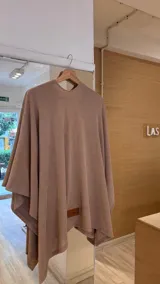 Ruana de tejido de punto fino en color beige, con diseño abierto y caída fluida.