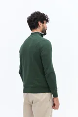 Sweater de tejido liso color verde oscuro, con cuello medio y cierre frontal parcial plateado. Presenta puños y cintura acanalados, y un pequeño logo bordado en el pecho.