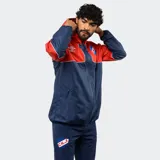 Campera de lluvia Umbro del Club Nacional de Football, con diseño de bloques de color blanco y azul marino. Presenta capucha, cierre frontal completo, puños elásticos y detalles de piping en color rojo. Incluye logo de la marca y escudo del club en el pecho.