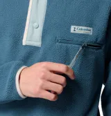Buzo polar de cuello alto con cierre de botones a presión, manga larga y bolsillo frontal con cremallera en el pecho. Presenta un diseño retro con detalles en contraste en el cuello y la solapa.