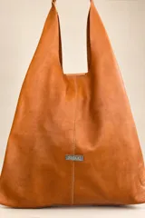 Bolso tipo tote de gamuza azul marino, de gran capacidad y diseño flexible, con asas largas de cuero marrón oscuro y placa metálica con la marca grabada en la parte frontal.