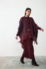 Ruana artesanal tejida en lana, con diseño de trama multicolor en tonos bordó, violeta y naranja, terminada con flecos en los extremos.