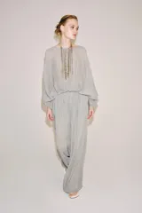 Pantalón palazzo gris de tejido semitransparente con tiro medio, cintura elástica, bolsillos laterales y forro interior corto.