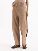 Pantalón de microfibra de textura liviana en color beige, con silueta de pierna ancha y calce fluido. Posee cintura alta con cinturón forrado a juego, hebilla cuadrada, ojalillos metálicos, bolsillos laterales y recortes con tajos en los laterales.