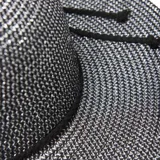 Sombrero de ala ancha color negro con detalle de cinta marrón.