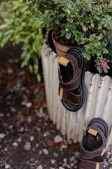 Sandalias marrones con tiras de cuero con ajuste de velcro y detalles en amarillo.