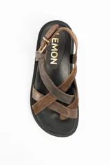 Sandalias de cuero marrón con tiras cruzadas en el empeine, suela chunky negra y hebilla metálica de ajuste en el talón.