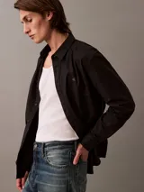 Camisa negra de manga larga con cuello abotonado y logo de Calvin Klein bordado en el pecho.