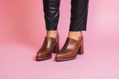 Zapato de cuero color marrón con elástico en los laterales y detalle de cuero texturizado en el talón y la suela.