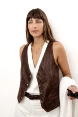 Chaleco de cuero vacuno color coñac, con escote en V y cierre frontal de botones dorados envejecidos.