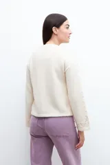 Sweater color beige claro con cuello redondo y detalle calado en el frente y mangas. Corte holgado.