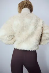 Campera de sherpa suave con cuello elevado acanalado y cierre frontal. Modelo con bolsillos laterales discretos, bolsillo interior y cordones para ajustar en el bajo.