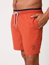 Short de baño Polanco modelo Loraz, color coral, con cintura elástica, cordón ajustable blanco y negro, bolsillos laterales y pequeño logo circular estampado en la pierna.