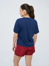 Remera de fútbol Umbro del Club Nacional de Football, modelo Bink para mujer. Diseño azul oscuro con cuello redondo y mangas cortas, con logo de Umbro en el pecho derecho y escudo del club en el pecho izquierdo.