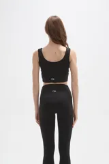 Top deportivo de bretel ancho, color negro, con cuello redondo profundo y diseño ajustado al cuerpo.