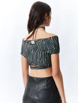 Top negro con estampado floral, escote off-shoulder, corte cruzado y mangas cortas.