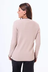 Buzo de tejido de punto acanalado en color beige, con cuello alto y terminaciones con borde ondulado en contraste negro en cuello y puños.