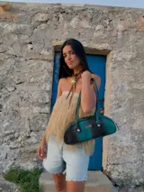 Cartera baguette de cuero marrón con manijas largas y detalle de nudos esféricos de alpaca en la unión de las manijas.