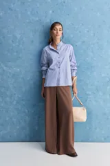 Camisa de rayas blancas y azules con cuello mao decorado con volados sutiles, cierre frontal de botones y mangas largas.