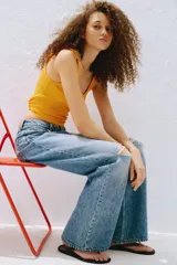 Jean de tiro alto confeccionado en denim de algodón lavado con diseño de cinco bolsillos, piernas rectas y holgadas, y detalles de roturas en las rodillas.