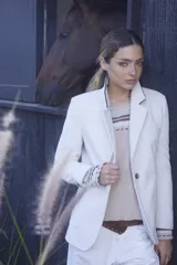 Blazer de pana color crema con solapas clásicas, cierre frontal de un botón y puños con detalle de tejido a rayas. Presenta un corte estructurado y elegante.