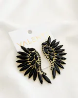 Par de caravanas con forma de ala, con incrustaciones de piedras negras y detalles dorados.