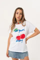 Remera blanca de manga corta con estampa frontal de cerezas y la frase 'Not your baby'. Presenta un corte holgado con mangas caídas y dobladillo ligeramente más largo en la parte posterior.