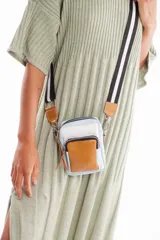 Bandolera pequeña de cuero sintético tricolor: celeste, blanco y marrón. Tiene correa larga regulable de tela con rayas negras y blancas.