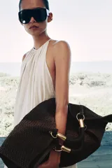 Maxi bolso color marrón con efecto rafia, doble asa de mano rígida con detalles metálicos dorados y cierre con botón imantado.