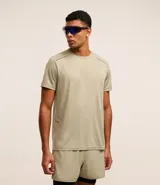 Remera deportiva de hombre con tecnología Dry, cuello redondo y mangas cortas. Presenta un diseño minimalista en color beige con detalles de líneas en los hombros y estampado reflectante.
