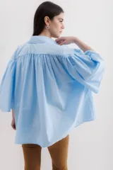 Camisa marrón con cuello clásico, abotonada al frente y mangas 3/4 abullonadas.