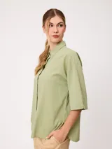 Camisa de manga corta celeste, confeccionada en mezcla de algodón y lino, con cuello camisero y cierre frontal de botones.